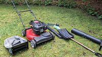 Full lot view: mower, catcher bag on ground, shovel blade, black chute, sprayer