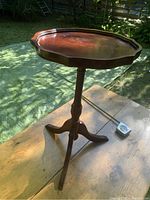 Side view of the tripod formal side table with piecrust edge, highlighting the curved legs and turned pedestal base.