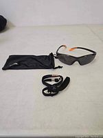 Belzig sunglasses displayed with black drawstring storage pouch and black adjustable neck strap