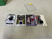 Four sports cards displayed on table, each showing player image, autograph or jersey patch.