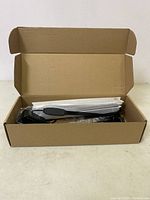 LED grow light panel and accessories inside open cardboard box showing power adapter with inline switch and hanging hardware wrapped separately.