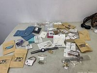 Wide view of assortment of costume jewelry items spread on table including kraft bags, plastic bags, and jewelry cards.