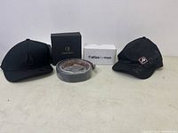 Overview of lot with two adjustable caps, belt, and boxed alarm clock