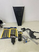 Lot of miscellaneous new tools and accessories laid out on a table, includes two Irwin drill gauges, a chain wrench, drill adapter, and other small tool parts.