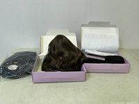 Two new wigs in pink Paula Young branded boxes, one wig brown and wavy, displayed open with packaging and netting included.