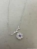 Full view of the silver flower pendant and part of the chain laid flat.