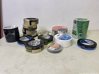 Assorted tapes including Scotch contractor grade, Painter's Mate green painter's tape, white double-sided carpet tape, black and blue tape rolls.