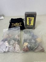Tarot deck of cards in original box alongside two sealed bags containing assorted stones and one black pentacle symbol cloth bag.