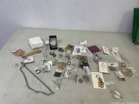 Overview of assorted costume jewelry on white table including necklaces, bracelets, rings, earrings, some in packaging.