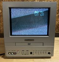 Front view of the Sylvania CRT television with the screen displaying static and part of an on-screen channel number (CH 28). Shows front panel controls and RCA inputs.
