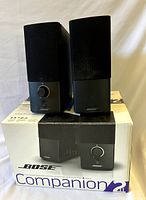 Front view of both black Bose Companion 2 Series III computer speakers placed on original box