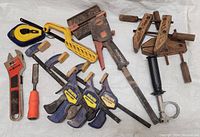 Overview photo showing all tools in lot including clamps, wrench, saw, chisel, tape measure and chalk container.