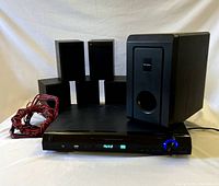 Full set including 5 satellite speakers, subwoofer, receiver unit with visible speaker wires on left.