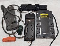 Lot contents showing all five power surge protectors and extension cords