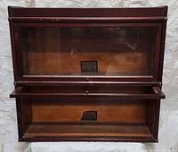 Two-section mahogany Globe-Wernicke barrister bookcase showing two glass-fronted compartments with lifted-up and open glass panels, visible labels inside.
