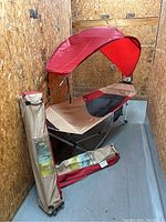 Two Ozark Trail hammocks set up showing tan and red fabric, mesh backrest, attached sunshade canopy, and carry bags standing upright beside them.