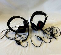Two PC headsets with microphones lying on a flat surface, showing their cables and connectors.