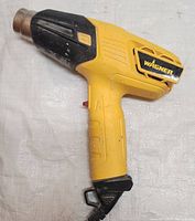 Side view of yellow Wagner heat tool showing ergonomic handle, on/off switch, and metal heat nozzle.