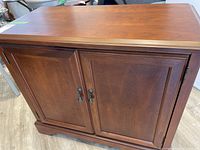 Front view of Bombay Company wooden cabinet with two doors and metal handles.