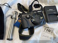 Camera with Nikon strap, battery charger, and mini tripod
