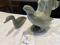 Photo showing both stone bird carvings on a table from a side angle to show form and size.