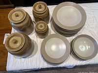 Overview of the Denby Intro dinnerware plates and bowls, and four Northwind lidded storage jars arranged on a white cloth.