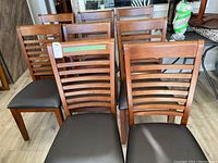 Front view of eight chairs arranged in two rows showing ladderback design and vinyl seats