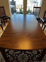 Top view of wood dining table set with chairs, showing butcher block style finish.