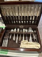 Open wooden chest showing top rack of 12 knives and bottom section with assorted forks, spoons and accessories
