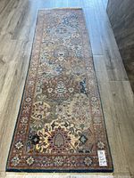 Full view of the rectangular hall carpet laid flat on a wood floor showing the entire patterned surface with red-brown border and central floral motifs.