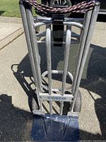 Front view of Cosco handtruck showing aluminum frame, base plate, and bungee cord across the top.