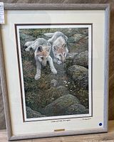 Full view of the framed print showing the two wolf pups and surrounding tundra landscape with rocks and grass.