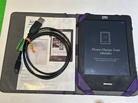 Kobo eReader placed in a protective case with the charging cable and user manual shown inside the case.