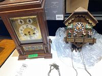 Wide shot of wooden mantel clock and chalet-style cuckoo clock on tabletop