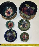 Top down photo showing all six pottery items arranged on a white surface with a measuring tape for scale.