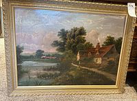 Overall view of the framed painting showing cottage by water and surrounding landscape