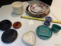 Overall view of plates stacked with visible ruler showing scale, surrounded by pottery and plant bases arranged around.