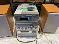 Front view of Sony portable stereo main unit with two speakers, showing control knob, cassette and CD sections, and wiring