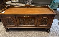 Front view of carved wood chest showing three decorative panels and bun feet