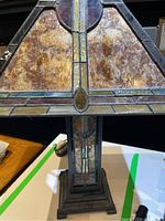 Close-up of the front stained glass style panels on the lampshade showing warm amber, yellow, green and reddish hues and geometric design.