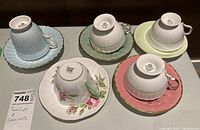Top view of the five bone china teacups upside down on their saucers showing varied floral and pastel colored patterns.