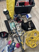 Photo showing various tools including thermos, box, levels, brushes, and toolbelt inside a plastic tote.