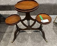 Front view showing three round wooden tops and carved wooden base on carpeted floor