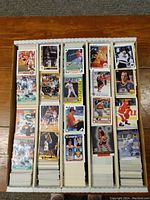 Top view of five dense rows of sports cards, displayed face up showing hockey, baseball, basketball, and football cards from the 1990s.