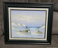 Full view of the framed painting showing a beach scene with figure and seagulls, artist signed.