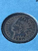 Obverse side of the 1900 Indian Head penny showing the profile of a Native American in a feathered headdress with 'UNITED STATES OF AMERICA' and the year 1900.