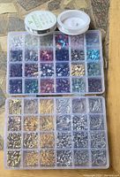 Plastic case with small compartments holding assorted colorful beads and two small containers, one with white beads, the other empty lid.