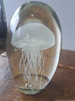 Front view of the glass paperweight showcasing the detailed white jellyfish design inside clear glass with small air bubbles.
