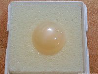 Close-up of the round dome-shaped moonstone showing its smooth surface and cat's eye effect.