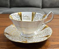 Tea cup and saucer from a side angle showing the shape and partial decoration.